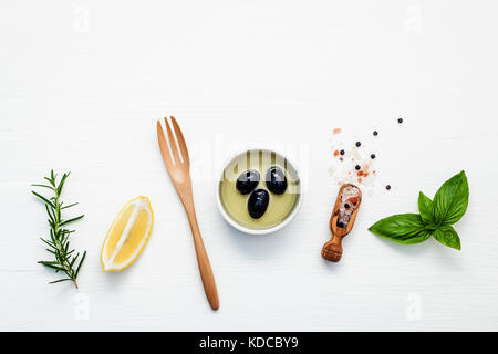 Vinaigrette au basilic ingrédients sur fond de bois blanc avec une télévision jeter les feuilles de basilic sucré frais, citron, huile d'olive et d'olive noire, lui Banque D'Images