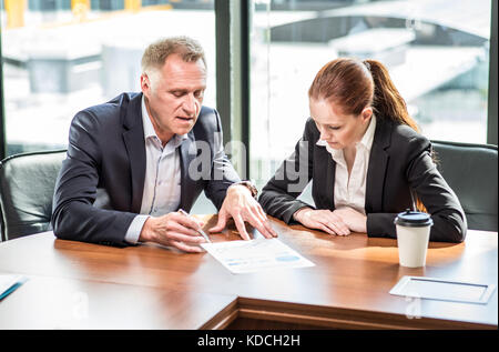 L'homme d'affaires à maturité et sa jeune assistante assis à table de réunion in office Banque D'Images