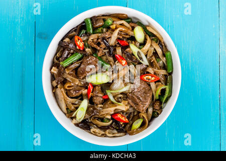 Style chinois wok de boeuf sauté aux champignons et les nouilles sur un fond de bois bleu Banque D'Images