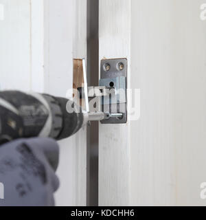 Un ouvrier installe un près dissimulé d'une nouvelle porte d'incendie dans le cadre de la rénovation d'un immeuble résidentiel à Londres, au Royaume-Uni. Banque D'Images