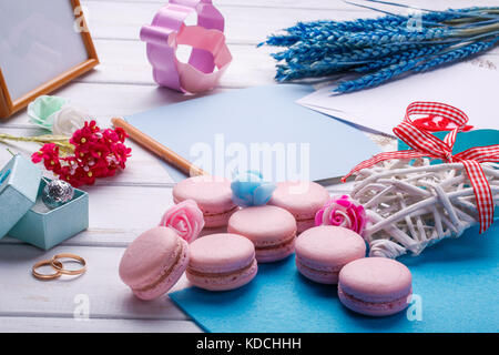 Macarons en forme de coeur rose et les anneaux de mariage avec carte postale. lieu d'inscription de la Saint-Valentin. Banque D'Images