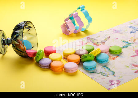 Délicieux macarons colorés dans un verre sur fond jaune peut être utilisé pour le papier peint vintage Banque D'Images