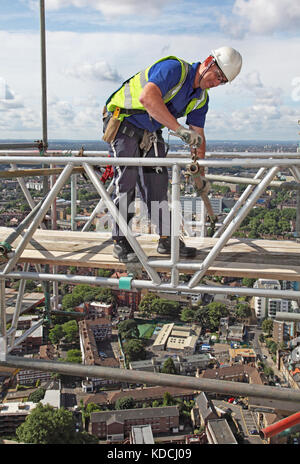 Un scaffolder érige une plate-forme de travail temporaire au-dessus de Londres pendant la rénovation de la tour de l'hôpital les gars. Southwark & Bermondsey montre au-delà. Banque D'Images