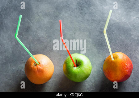 Les fruits mûrs colorés pamplemousse mangue pomme avec des pailles des jus detox santé nettoyage ethnique. arrière-plan foncé modèle d'affiche menu Copier l'espace. Banque D'Images