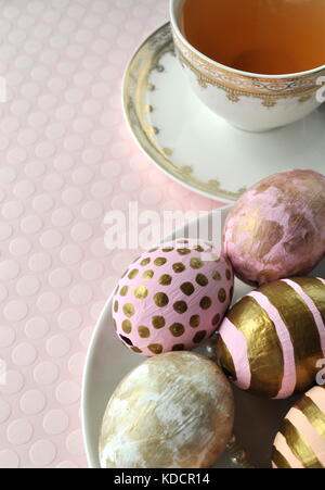 Or les oeufs de Pâques décorés à pois et de rayures sur fond rose Peach blush. Image Style avec copie espace. Thème de Pâques et du printemps. Banque D'Images