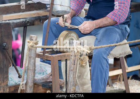 Asti, ITALIE - 10 septembre 2017 : blacksmith aiguise la hache avec une pierre abrasive Banque D'Images