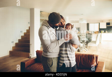 Jeune père et mère tenant leur bébé garçon. Les parents de passer du temps avec fils nouveau-né à la maison dans le salon. Banque D'Images