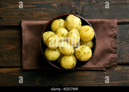 Des pommes de terre bouillies avec de l'aneth dans un bol sur fond de bois, vue du dessus Banque D'Images