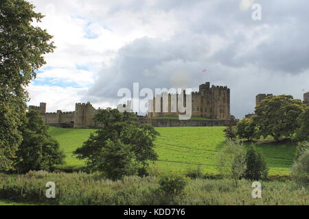 Château d'Alnwick en vertu de la fin de l'été, les nuages de tempête vue depuis le nord en regardant vers le sud sur la rivière Aln à travers un parc, Alnwick, Northumberland, Angleterre Banque D'Images