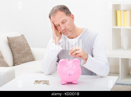 Portrait d'un homme fatigué d'Insérer coin In Piggybank Banque D'Images