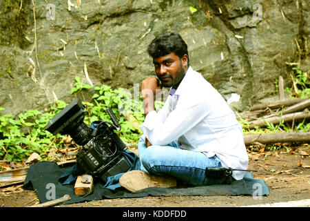 Jeune homme dans l'implantation sur le terrain, caméra vidéo et poser l'homme looking at camera Banque D'Images