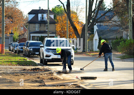 Les bénévoles de balayer la rue devant un chantier à London, Ontario au Canada. Banque D'Images