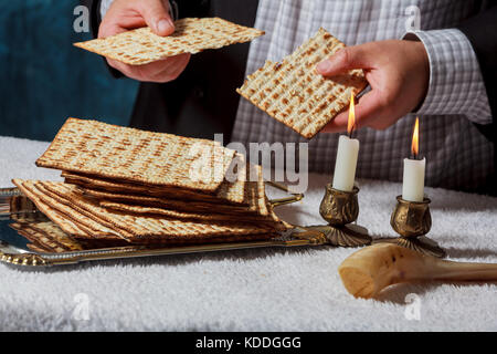 Les hommes juifs est bénédiction sur la matsa pain sans levain pendant qu'un autre portant une kippa scutellaire lit le texte traditionnel de la Haggadah au cours de bénédictions pour les Banque D'Images