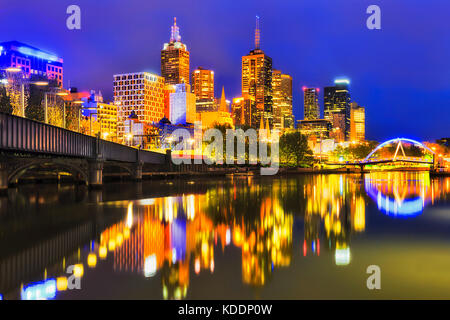 La ville de Melbourne, brillant lumineux reflétant lumières dans les eaux calmes de la rivière Yarra entre 2 passerelles au lever du soleil. Banque D'Images