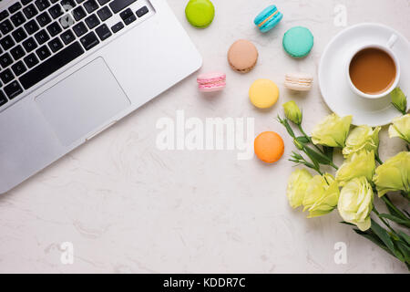 24 avec blanc macarons colorés, fleurs, ordinateur portable, portable et tasse de café Banque D'Images