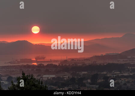 San Francisco, USA. Oct 12, 2017. À l'ouest à travers la baie de San Francisco à la recherche au-dessus de Point Richmond au coucher du soleil par une traînée de fumée au-dessus des Marin Headlands, au sud de la Sonoma et Napa de friches. La qualité de l'air sur cette journée a été considéré comme mauvais à San Francisco comme à Beijing en Chine. 12 octobre, 2017. Credit : Shelly Rivoli/Alamy Live News Banque D'Images