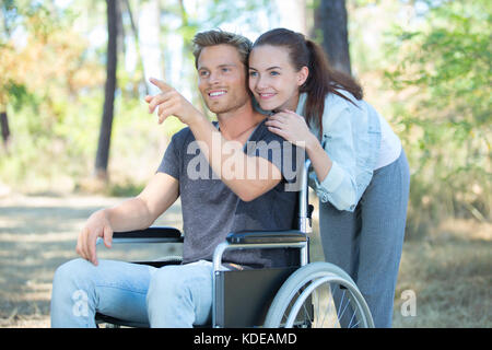 Couple aimant la marche à l'extérieur en fauteuil roulant Banque D'Images