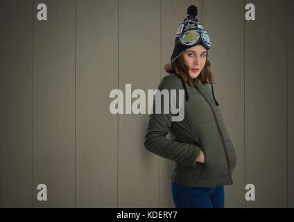 Digital composite of Woman contre le bois avec des vêtements chauds et des lunettes de ski Banque D'Images
