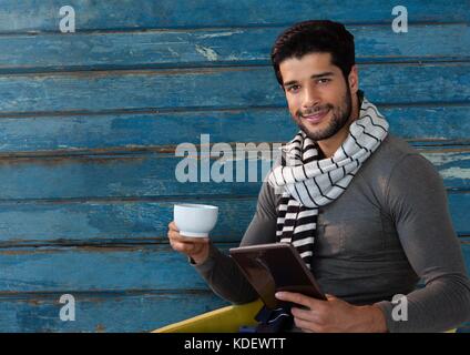 Digital composite de l'homme contre le bois avec écharpe et tasse et tablette Banque D'Images