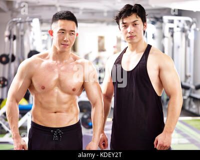 Portrait de deux jeunes bodybuilders asiatique posant dans une salle de sport. Banque D'Images