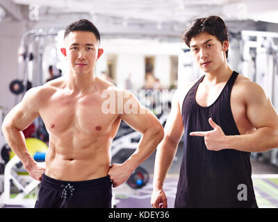 Portrait de deux jeunes bodybuilders asiatique posant dans une salle de sport. Banque D'Images