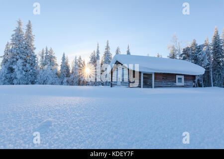 Sunburst sur cabane en bois couverte de neige, Kiruna, comté de Norrbotten, Lapland, Sweden Banque D'Images