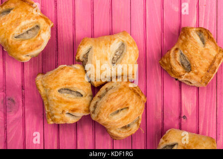 Pile la pile ou la sélection de rouleaux de saucisses de porc salés en croûte sur un fond de bois de rose Banque D'Images