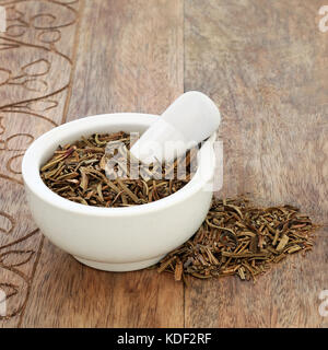 Le yerba santa herbe utilisée dans la médecine alternative pour traiter la toux, le rhume, l'asthme et la bronchite dans un mortier avec un pilon sur fond de bois rustique. Banque D'Images