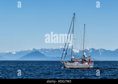 Un voilier définit l'ensemble du détroit de Géorgie en Colombie-Britannique sur une journée froide et claire au début du printemps (l'île de Bowen, Howe Sound et plage de la côte en arrière-plan). Banque D'Images