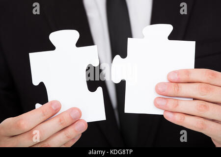 Close-up of a businessman solving puzzle in office Banque D'Images