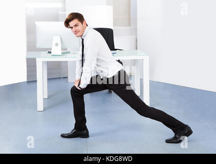 Portrait of a young businessman stretching in office Banque D'Images