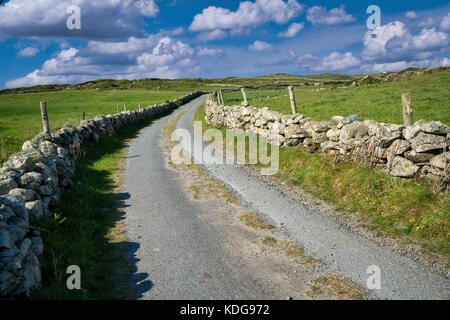 Couple marchant sur la route sur Omey Island. Connemara, comté de Galway, Irlande Banque D'Images