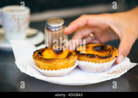 Attrapant la main de pâtisserie typiquement portugaise - pastel de nata, également appelé pastel de Belem. Banque D'Images