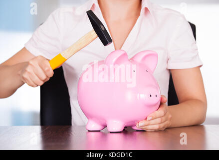 Close-up of woman holding hammer sur piggybank Banque D'Images