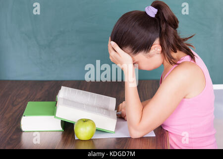 Portrait of young female student écrit sur papier à côté de green apple Banque D'Images