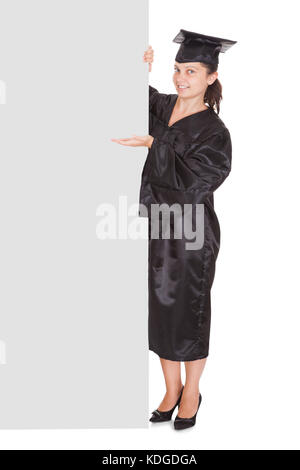 Graduate woman holding blank placard sur fond blanc Banque D'Images