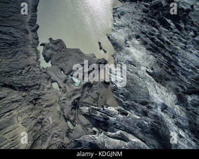 Vue aérienne d'un glacier en Islande, de l'eau de fusion glaciaire formant une rivière devant elle Banque D'Images