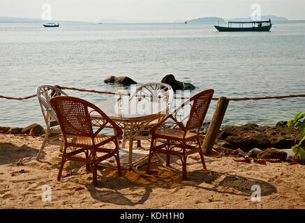 Table avec chaises en osier sur le littoral, la plage locations Banque D'Images