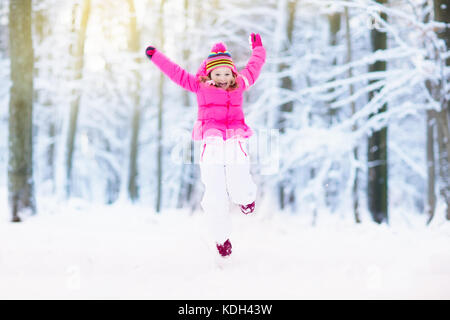 Enfant jouant avec la neige en hiver. petite fille au chapeau tricoté veste colorée et attraper des flocons de neige en hiver Parc sur Noël. les enfants à jouer et sauter Banque D'Images