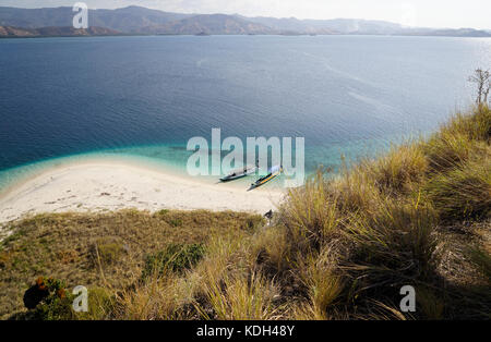 Vue de dessus de deux bateaux à la côte d'une plage de sable blanc entourée d'eau de mer couleur turquoise bleu de flores en Indonésie. Banque D'Images