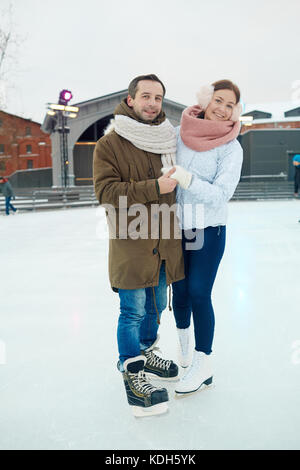 Cheerful dates affectueux en patins et winterwear consacrent ensemble Banque D'Images