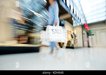 Se dépêchant shopper avec paperbags se déplaçant le long de la fenêtre d'affichage sur le black friday Banque D'Images