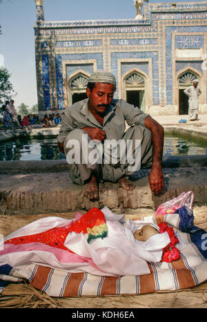 Un homme pleure sur le corps de son fils sur la tombe de Bibi à Jawindi UCH. Banque D'Images