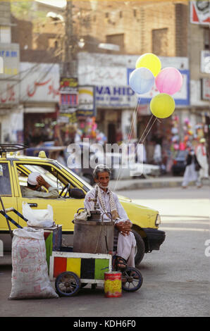 Un vendeur de rue avec des ballons et une charrette à Peshawar, au Pakistan, au milieu d'une circulation très fréquentée. Banque D'Images
