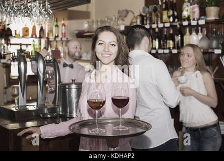 Smiling mordiller servant les clients avec les boissons bar Banque D'Images