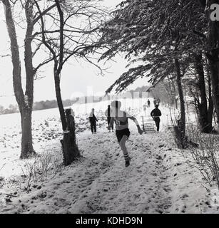 Années 1960, historiques, l'hiver et les concurrents prenant part à une course cross-country course à travers un champ couvert de neige et de forêts, à côté de l'Angleterre. Banque D'Images