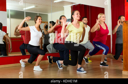 Happy smiling habillé de remise en forme les gens danser activement dans une salle de sport Banque D'Images