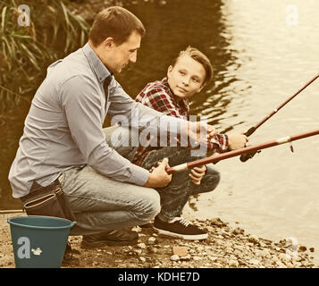 Famille de deux pêche ensemble sur l'eau douce à partir de la rive du lac Banque D'Images