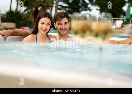 Jeune couple à l'intérieur d'un jacuzzi et dégustation de vin Banque D'Images