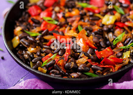 Ragoût de haricots noirs avec poivrons et tomates avec sauce épicée dans une casserole. Banque D'Images